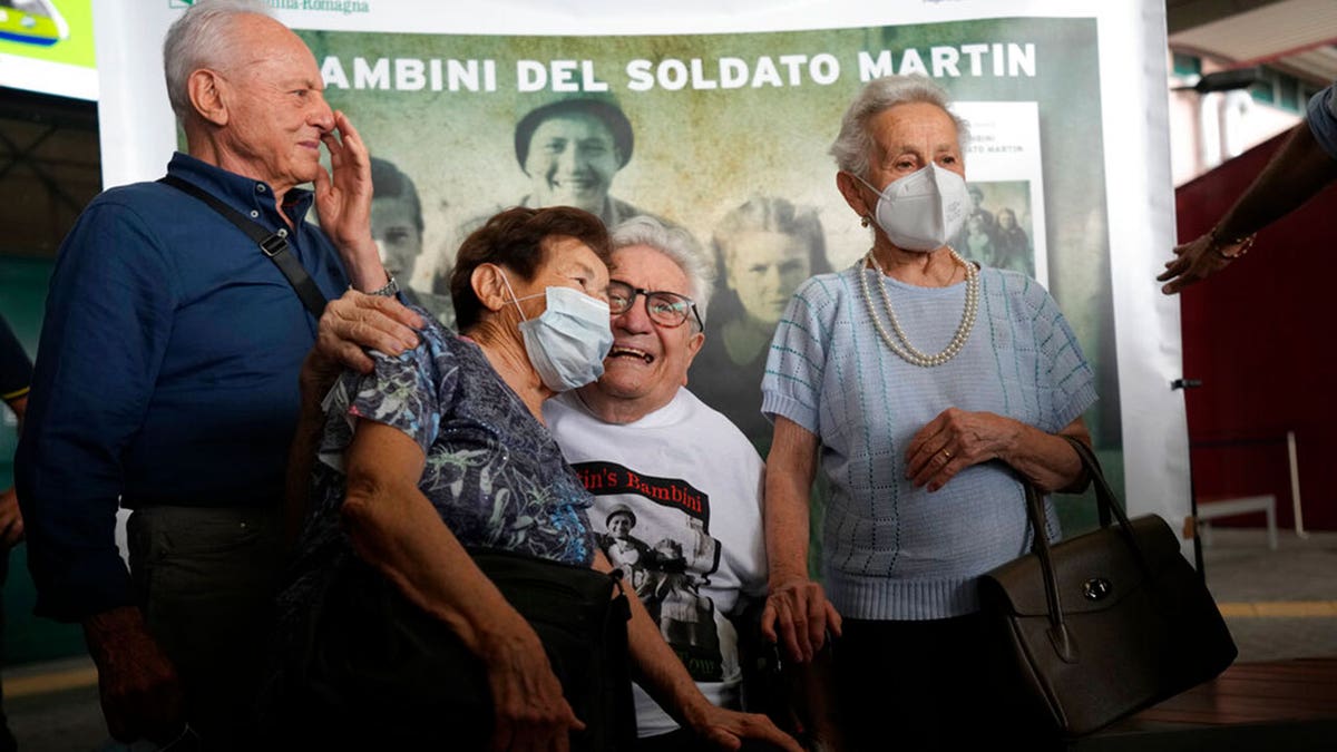 A 97 year old retired American soldier Martin Adler poses with Giulio, left, Mafalda, right, and Giuliana Naldi that he saved during a WWII at Bologna's airport, Italy, Monday, Aug. 23, 2021. For more than seven decades, Martin Adler treasured a back-and-white photo of himself as a young soldier with a broad smile with three impeccably dressed Italian children he is credited with saving as the Nazis retreated northward in 1944. The 97-year-old World War II veteran met the three siblings -- now octogenarians themselves -- in person for the first time on Monday, eight months after a video reunion.