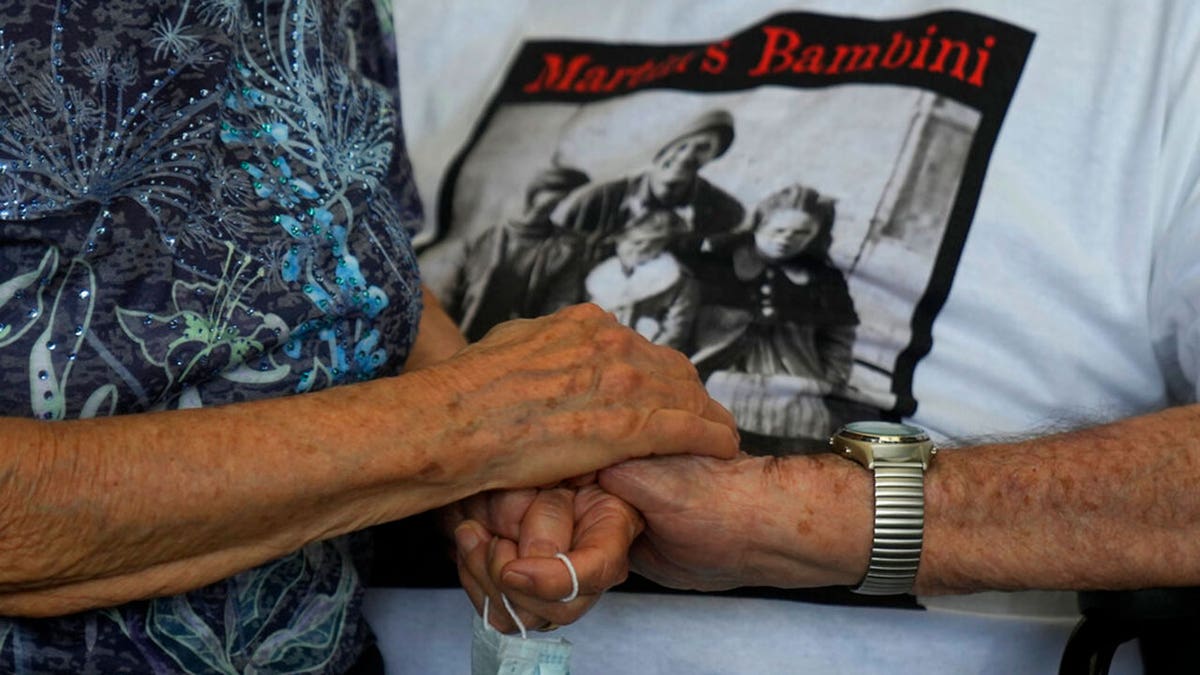 A 97 year old retired American soldier Martin Adler holds Giuliana Naldi's hand that he saved during a WWII, at Bologna's airport, Italy, Monday, Aug. 23, 2021. For more than seven decades, Martin Adler treasured a back-and-white photo of himself as a young soldier with a broad smile with three impeccably dressed Italian children he is credited with saving as the Nazis retreated northward in 1944. The 97-year-old World War II veteran met the three siblings -- now octogenarians themselves -- in person for the first time on Monday, eight months after a video reunion.