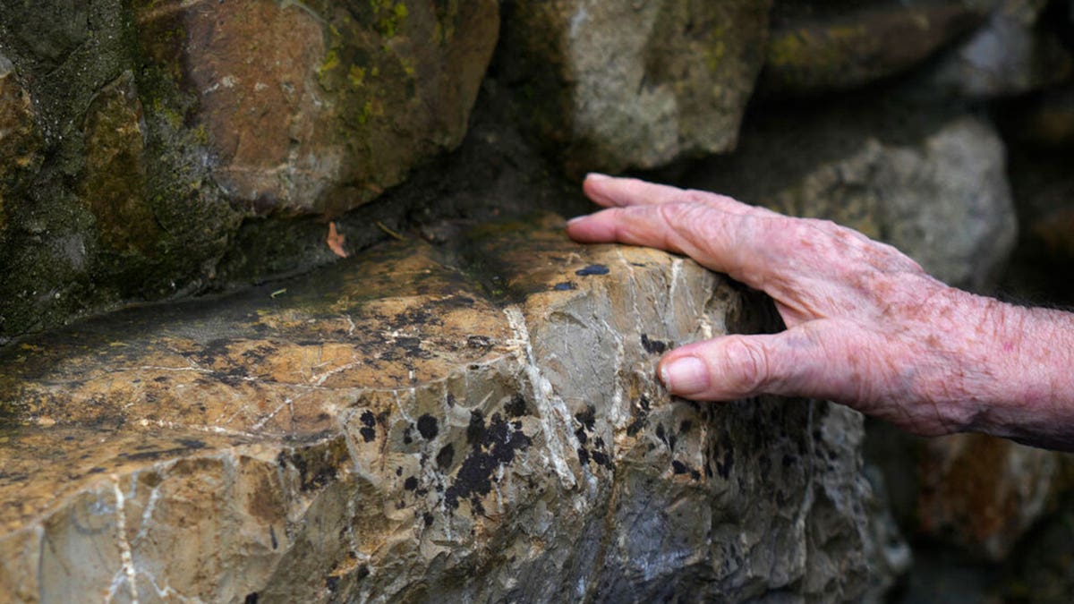 A 97 year old retired American soldier Martin Adler touches a rock where he was sitting with Giulio, Mafalda, and Giuliana Naldi to take picture after saving them during WWII, in Monterenzio, near Bologna, Italy, Monday, Aug. 23, 2021. For more than seven decades, Martin Adler treasured a back-and-white photo of himself as a young soldier with a broad smile with three impeccably dressed Italian children he is credited with saving as the Nazis retreated northward in 1944. The 97-year-old World War II veteran met the three siblings -- now octogenarians themselves -- in person for the first time on Monday, eight months after a video reunion.