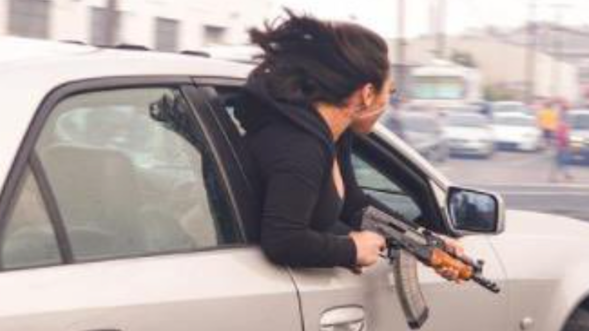 A photo out of San Francisco shows a woman leaning out of a moving car while holding an AK47.