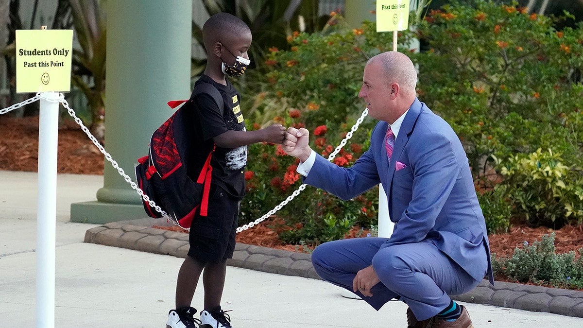 Addison Davis, Hillsborough County Superintendent of Schools, right, fist bumps student James Braden before he heads to class on the first day of school at Sessums Elementary School Tuesday, Aug. 10, 2021, in Riverview, Florida. Students are required to wear protective masks while in class unless their parents opt out.