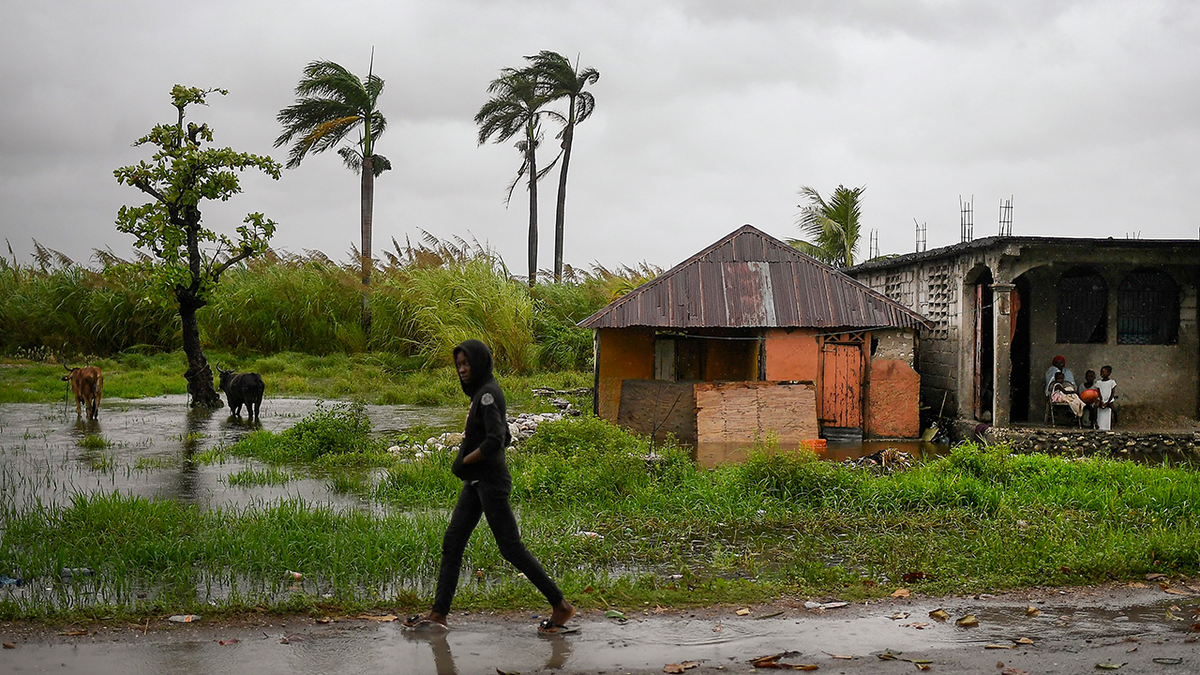 A man walks along a road in a slightly flooded area the morning after Tropical Storm Grace swept over the area in Trou Mahot, Haiti, Tuesday, Aug. 17, 2021, three days after a 7.2-magnitude earthquake.