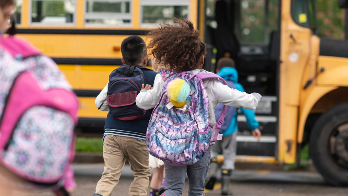 kids with backpacks going onto school bus