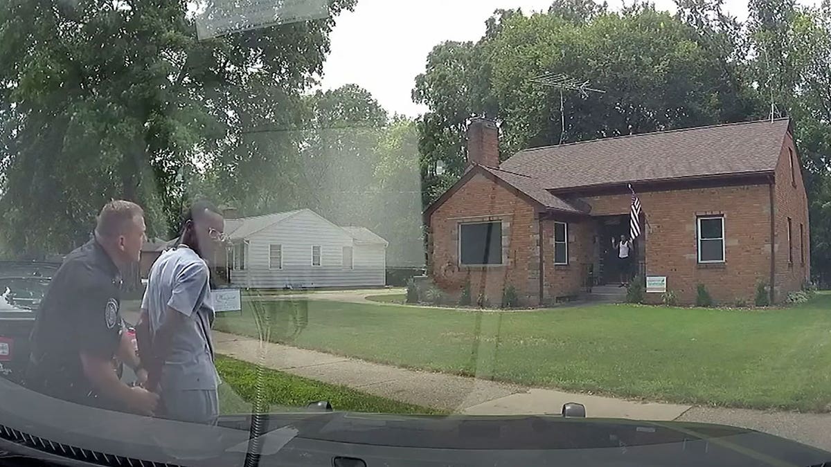 This Aug. 1, 2021 image from video provided by the Wyoming Police Department shows a Wyoming Officer handcuffing real estate agent Eric Brown outside a home he was showing to a potential buyer in Wyoming, Michigan. 