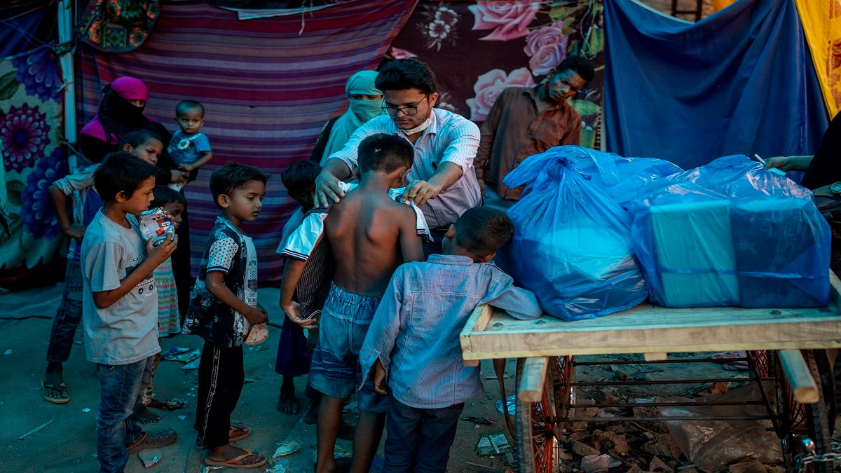 A Rohingya activist distributes new clothes among refugees at a refugee camp alongside the banks of the Yamuna River in the southeastern borders of New Delhi, sprawling Indian capital, on July 1. 