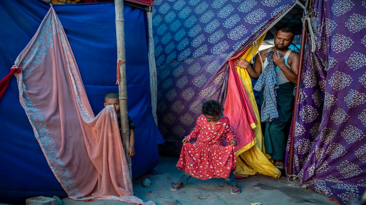 Kids play as Salimullah, 35, a Rohingya refugee comes out of his tent at a refugee camp alongside the banks of the Yamuna River in the southeastern borders of New Delhi on July 1. (AP)