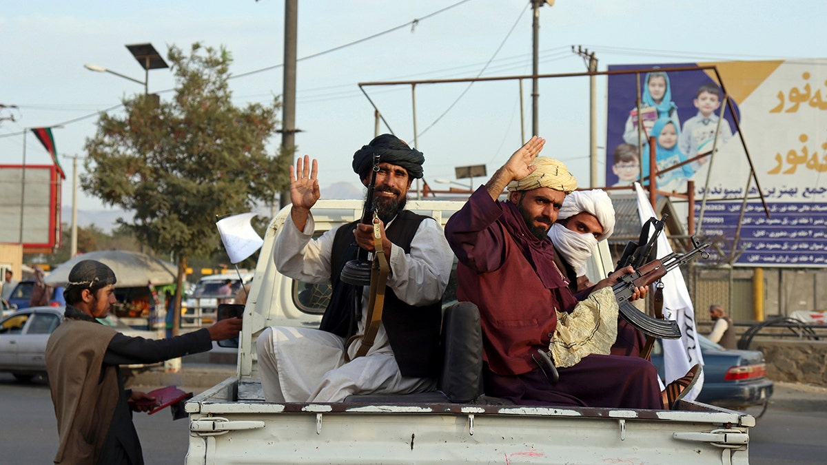 Taliban fighters wave from the back of a pickup truck, in Kabul, Afghanistan, Monday, Aug. 30, 2021. (AP Photo/Khwaja Tawfiq Sediqi)