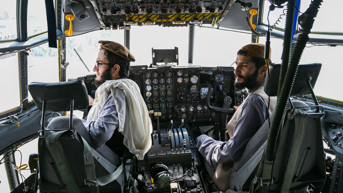 Taliban fighters sit in the cockpit of an Afghan Air Force aircraft at the airport in Kabul on August 31, 2021, after the US has pulled all its troops out of the country to end a brutal 20-year war -- one that started and ended with the hardline Islamist in power.