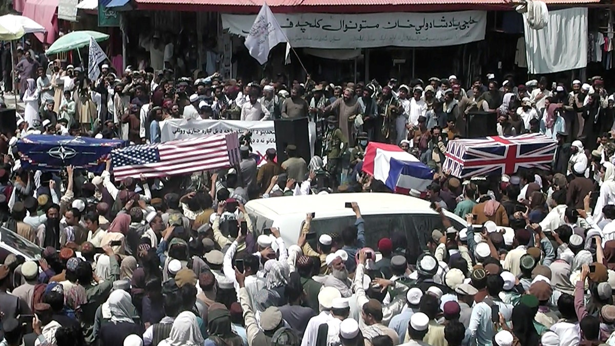 Crowd carries makeshift coffins draped in NATO's, U.S. and a Union Jack flags during a pretend funeral  on a street in Khost, Afghanistan August 31, 2021, in this screen grab obtained from a social media video. ZHMAN TV/via REUTERS 