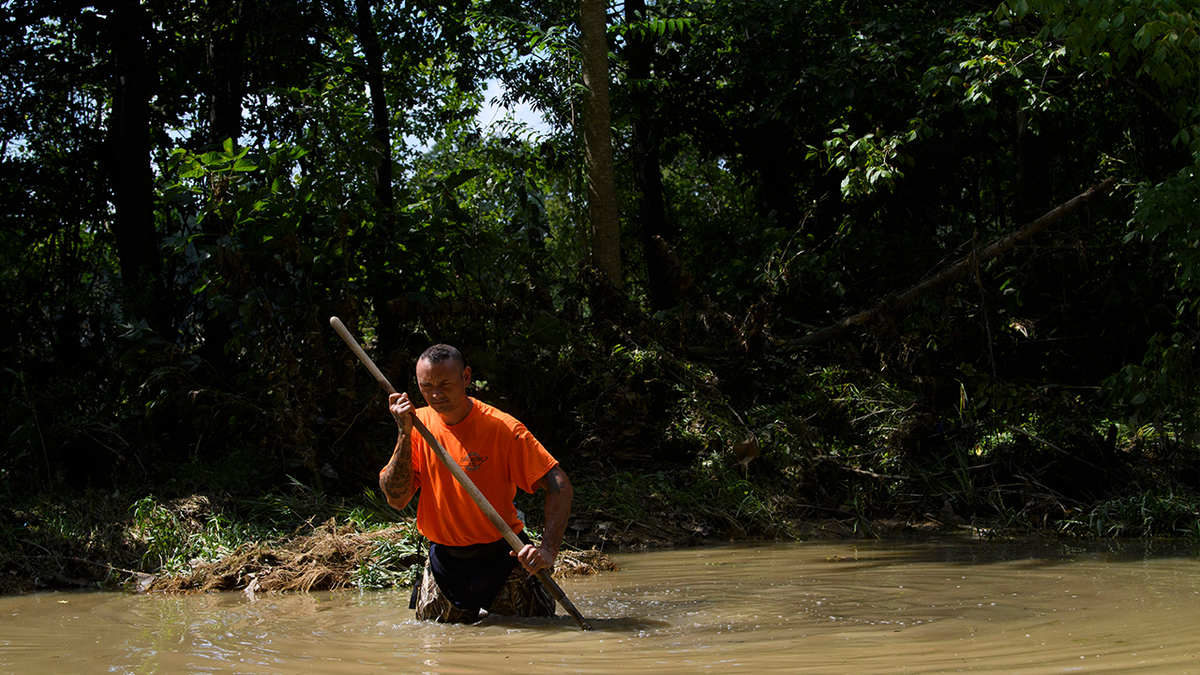 Dustin Shadownes, of Ashland City Fire Department, searches a creek for missing persons, Monday, Aug. 23, 2021, in Waverly, Tenn. Heavy rains caused flooding in Middle Tennessee days earlier and have resulting in multiple deaths, missing persons, and property destroyed.