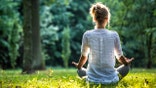 Young blonde woman meditating in the park