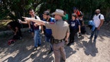 FILE - In this Wednesday, June 16, 2021 file photo, A Texas Department of Public Safety officer in Del Rio, Texas directs a group of migrants who crossed the border and turned themselves in. (AP Photo/Eric Gay, File)