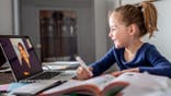 Little girl learns from home while her teacher teaches remotely.