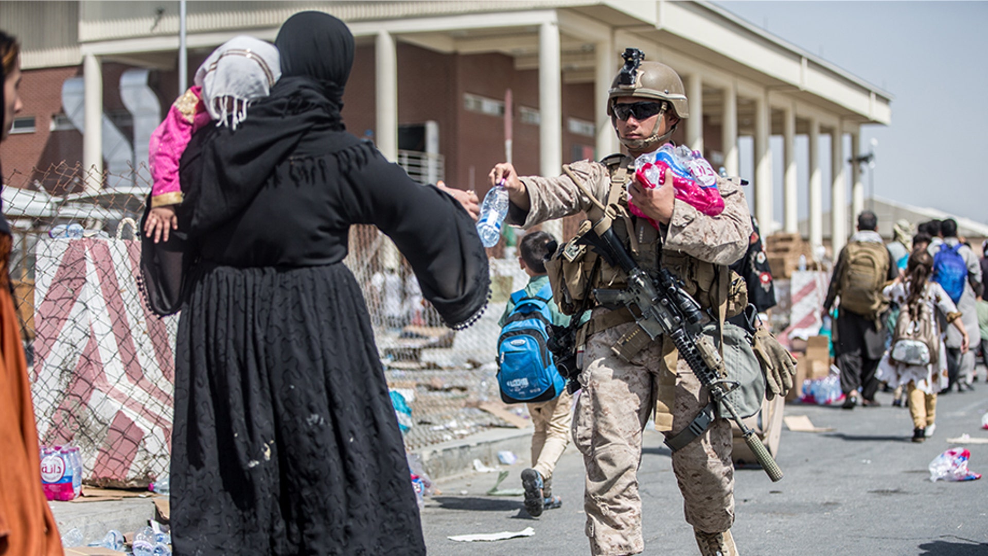 A Marine with Special Purpose Marine Air-Ground Task Force-Crisis Response-Central Command (SPMAGTF-CR-CC) provides water to families during an evacuation at Hamid Karzai International Airport, Kabul, Afghanistan, Aug. 22. U.S. service members are assisting the Department of State with an orderly drawdown of designated personnel in Afghanistan. (U.S. Marine Corps photo by Sgt. Samuel Ruiz).