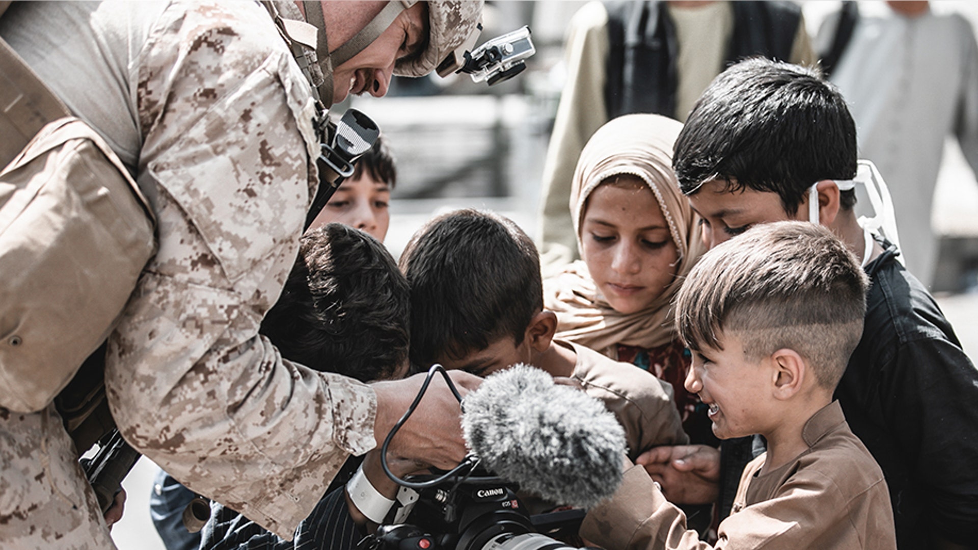 A U.S. Marine assigned to Special Purpose Marine Air-Ground Task Force – Crisis Response – Central Command shows his video camera to children awaiting evacuation at Hamid Karzai International Airport, Afghanistan, Aug. 22, 2021. The U.S. is assisting the Department of State with a Non-Combatant Evacuation Operation (NEO) in Afghanistan. (U.S. Marine Corps photo by Gunnery Sgt. Melissa Marnell)