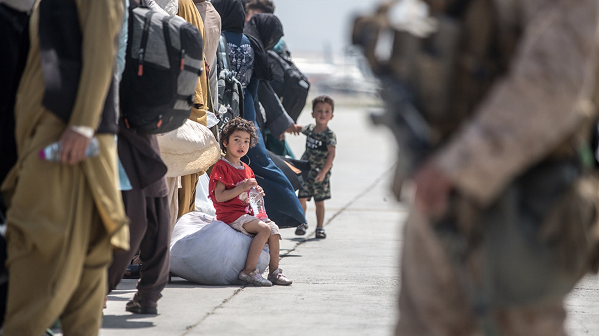 A child waits with her family to board a U.S. Air Force Boeing C-17 Globemaster III during an evacuation at Hamid Karzai International Airport, Kabul, Afghanistan, Aug. 22. U.S. service members are assisting the Department of State with an orderly drawdown of designated personnel in Afghanistan. (U.S. Marine Corps photo by Sgt. Samuel Ruiz).