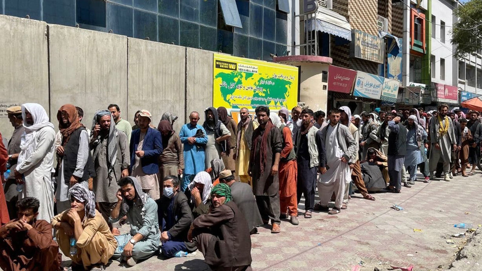 Afghans line up outside a bank to take out cash as people keep waiting at Hamid Karzai International Airport to leave the country after the Taliban's takeover in Kabul, Afghanistan, on Aug. 25, 2021. (Photo by Haroon Sabawoon/Anadolu Agency via Getty Images)