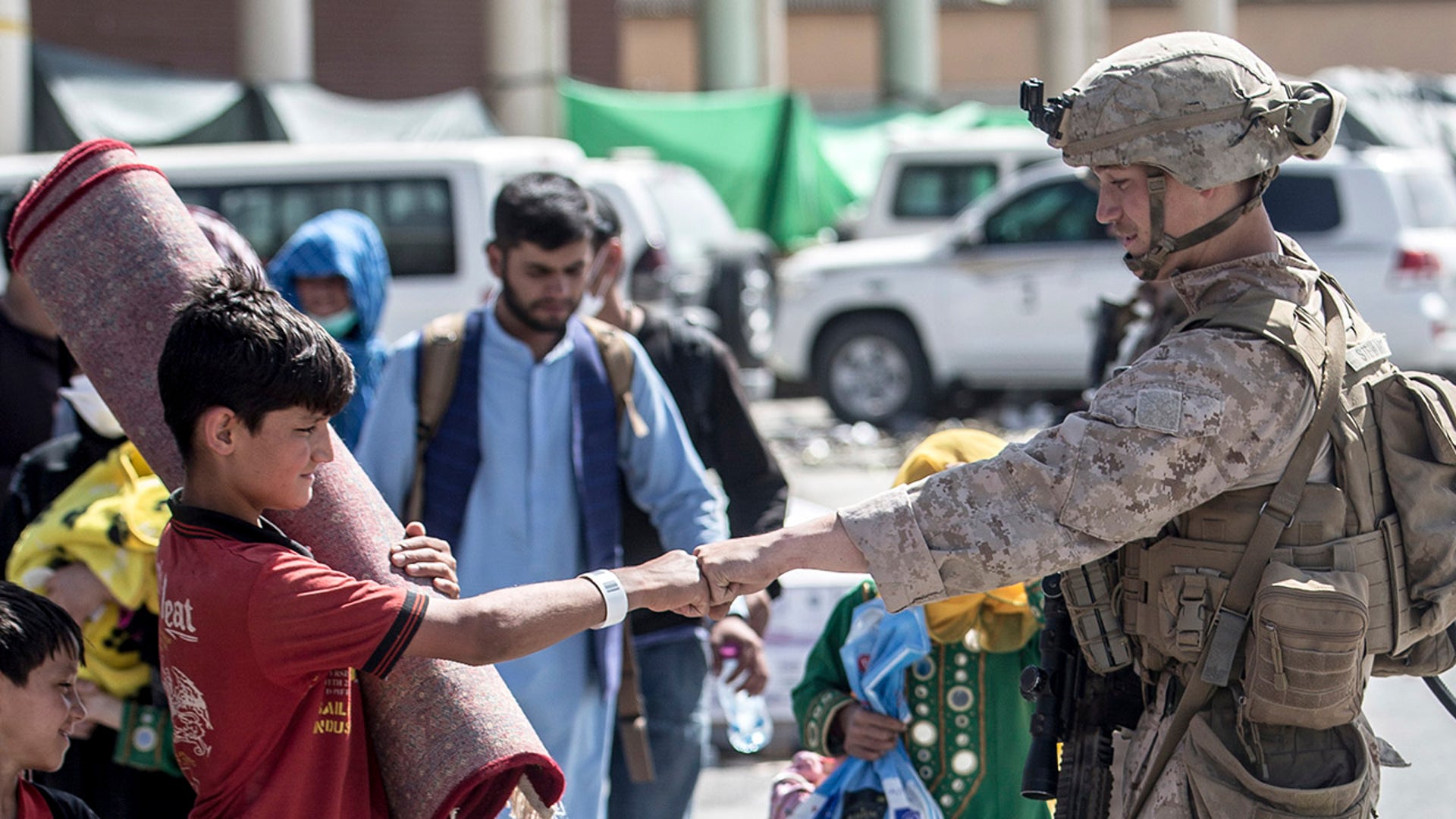In this image provided by the U.S. Marine Corps, a Marine with Special Purpose Marine Air-Ground Task Force-Crisis Response-Central Command shares a fist-bump with a child during an evacuation at Hamid Karzai International Airport in Kabul, Afghanistan, Tuesday, Aug. 24, 2021. (Sgt. Samuel Ruiz/U.S. Marine Corps via AP)