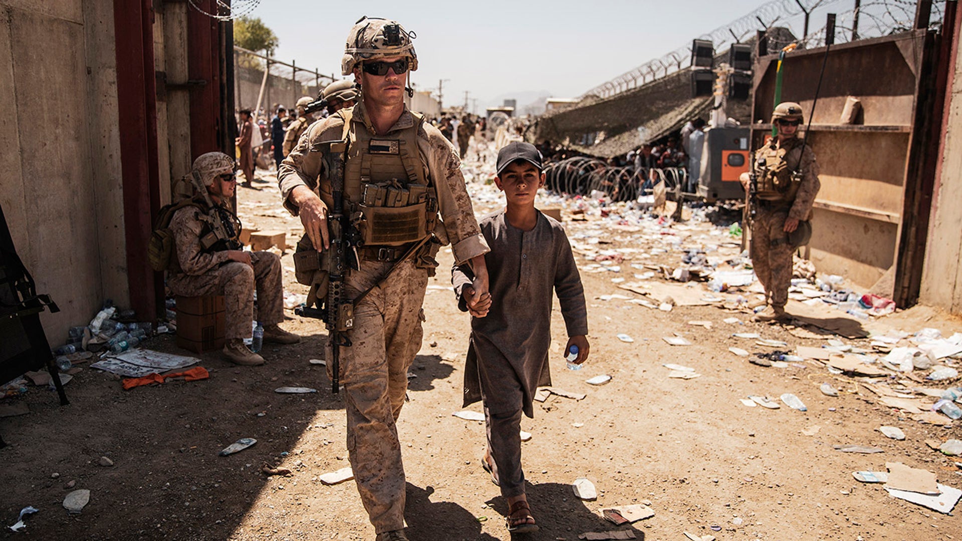 In this image provided by the U.S. Marine Corps, a U.S. Marine with the Special Purpose Marine Air-Ground Task Force-Crisis Response-Central Command escorts a child during ongoing evacuations at Hamid Karzai International Airport, Kabul, Afghanistan, Tuesday, Aug. 24, 2021. (Staff Sgt. Victor Mancilla/U.S. Marine Corps via AP)