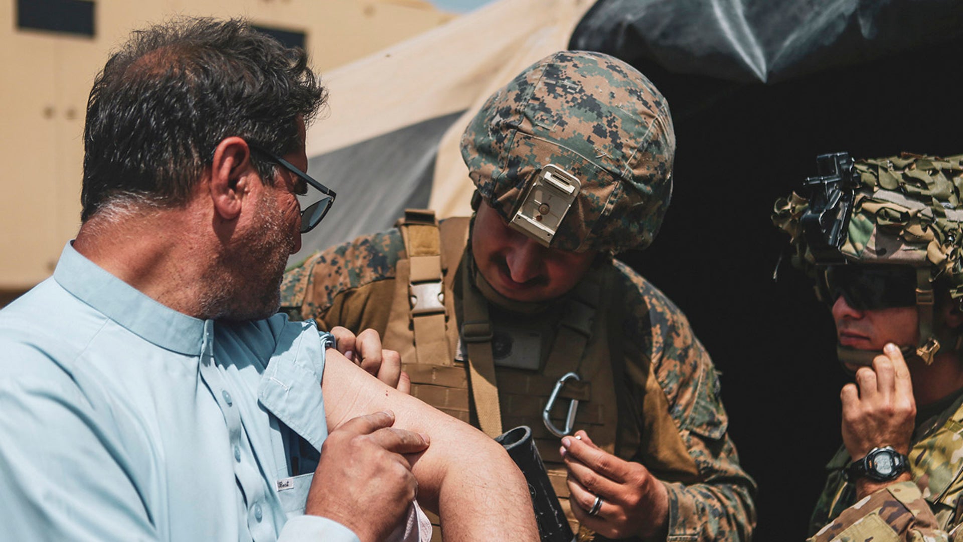 In this image provided by the U.S. Marine Corps, a corpsman assigned to the 24th Marine Expeditionary unit (MEU) and a Medic assigned to the 82nd Airborne Division assists an evacuee during an evacuation at Hamid Karzai International Airport in Kabul, Afghanistan, Sunday, Aug. 22, 2021. (Sgt. Isaiah Campbell/U.S. Marine Corps via AP)