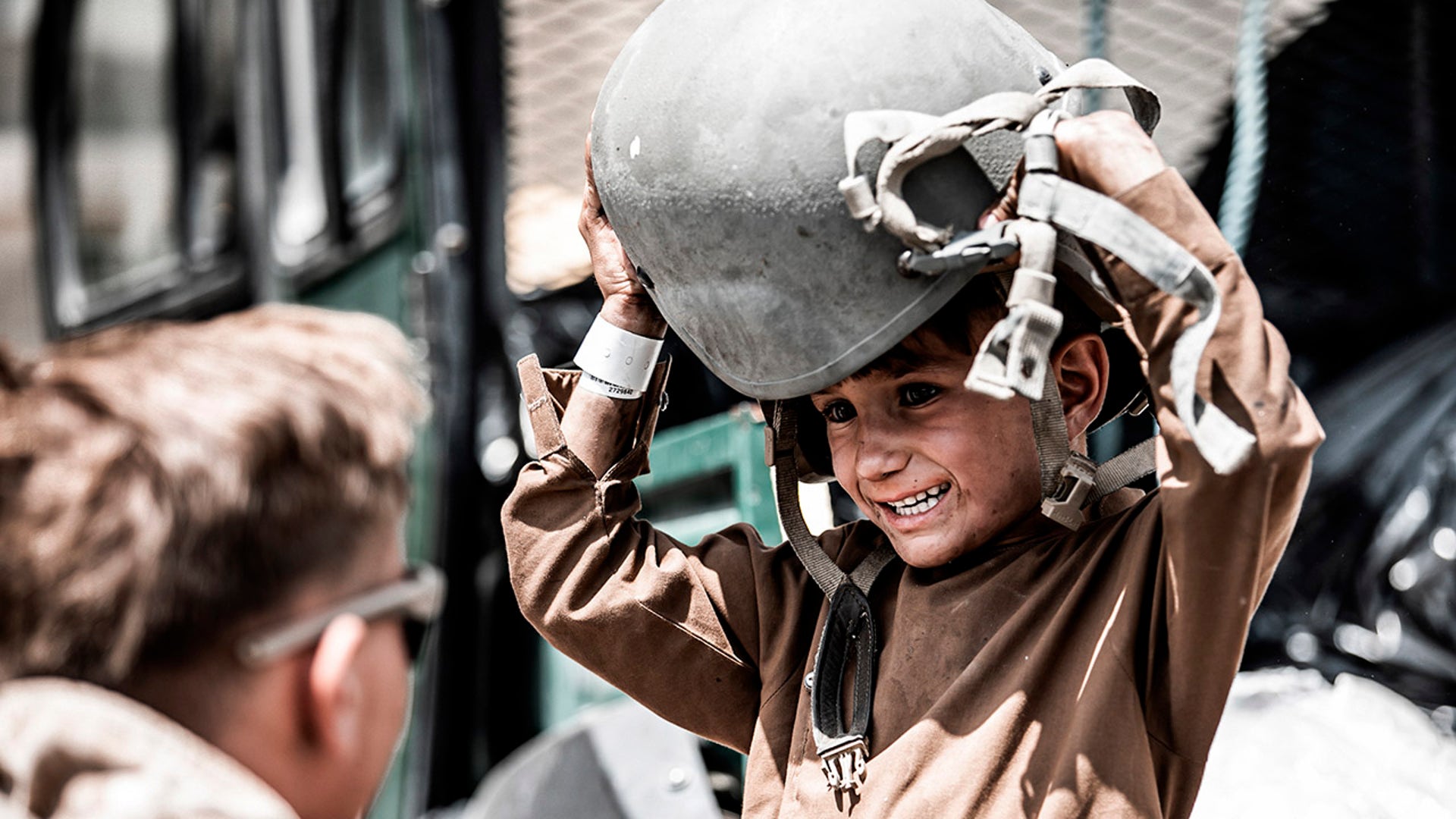 In this Aug. 22, 2021, photo provided by the U.S. Marines, a Marine assigned to Special Purpose Marine Air-Ground Task Force – Crisis Response – Central Command hands a helmet to a child awaiting evacuation at Hamid Karzai International Airport in Kabul, Afghanistan. (Gunnery Sgt. Melissa Marnell/U.S. Marine Corps via AP)