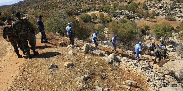 In this Oct. 8, 2014, file photo, Lebanese army soldiers and U.N. peacekeepers investigate near the site where Hezbollah had attacked on an Israeli patrol in the hills of Kfar Shouba village, near the Israeli-occupied Shebaa farms, southern Lebanon. The militant Hezbollah group said it fired a barrage of rockets near Israeli positions close to the Lebanese border on Friday, Aug. 6, 2021, calling it retaliation for Israeli airstrikes on southern Lebanon a day earlier. (AP Photo/Mohammed Zaatari, File)