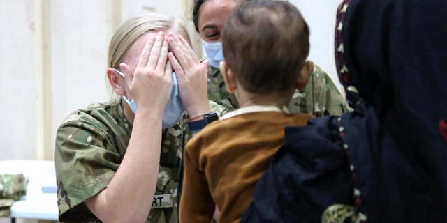 A U.S. Army National Guard Soldier with Task Force Spartan, U.S. Army Central, plays a quick game of peekaboo with an Afghan child who recently arrived at Camp Buehring, Kuwait, Aug. 23, 2021. U.S. Army Soldiers continue to work with their U.S. Central Command and Department of State teammates to support Afghanistan evacuation efforts with transportation, security, logistics and medical assistance at locations in Kuwait. (U.S. Army Photo by 1st Lt. James Mason)