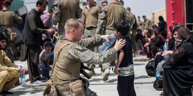 A Marine with the 24th Marine Expeditionary Unit (MEU) provides fresh water to a child during an evacuation at Hamid Karzai International Airport, Kabul, Afghanistan, Aug. 20. U.S. service members are assisting the Department of State with an orderly drawdown of designated personnel in Afghanistan. (U.S. Marine Corps photo by Sgt. Samuel Ruiz).