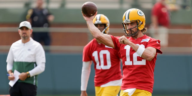 Green Bay Packers' quarterback Aaron Rodgers (12) passes while head coach Matt LaFleur and quarterback Jordan Love (10) watch during NFL football training camp Wednesday, July 28, 2021, in Green Bay, Wis.