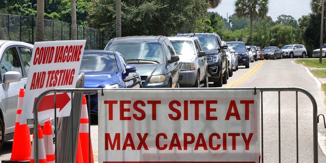 Signage stands at the ready, foreground, in case COVID-19 testing at Barnett Park reaches capacity, as cars wait in line in Orlando, Florida, Thursday, July 29, 2021. (Associated Press)
