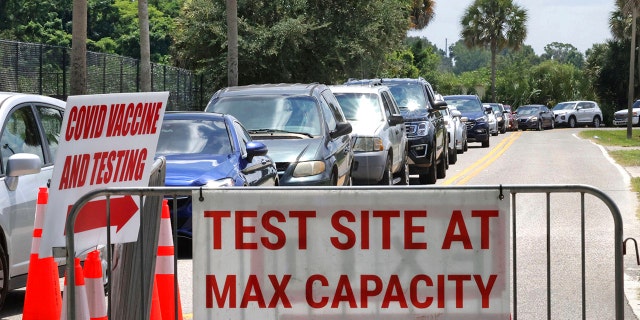 Signage stands at the ready (foreground) in case COVID-19 testing at Barnett Park reaches capacity, as cars wait in line in Orlando, Fla., Thursday, July 29, 2021.