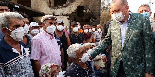 Turkey's President Recep Tayyip Erdogan speaks with villagers in front of a wildfire-destroyed house in Manavgat, Antalya, Turkey, July 31, 2021.  