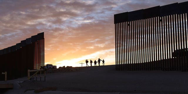 A pair of migrant families from Brazil pass through a gap in the border wall to reach the United States after crossing from Mexico to Yuma, Ariz., to seek asylum in June 2021.