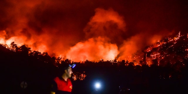 A man leaves as advancing fires rage the Hisaronu area, Turkey, Monday, Aug. 2, 2021. For the sixth straight day, Turkish firefighters battled Monday to control the blazes that are tearing through forests near Turkey's beach destinations.