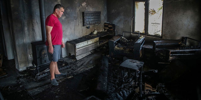 A man stands inside his burnt down house in the village of Cokertme, near Bodrum, Mugla, Turkey, Tuesday August 3, 2021.
