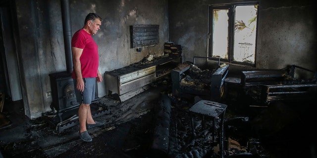 A man stands inside his burnt out house in Cokertme village, near Bodrum, Mugla, Turkey, Tuesday, Aug. 3, 2021.