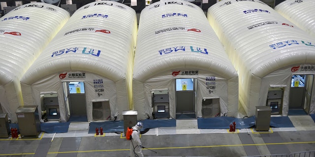 A worker disinfects the flooring outside the inflated cabins at the pop-up Huo-Yan Laboratory set up in an expo center to test samples for covid-19 virus in Nanjing in east China's Jiangsu province Wednesday, 칠월 28, 2021.