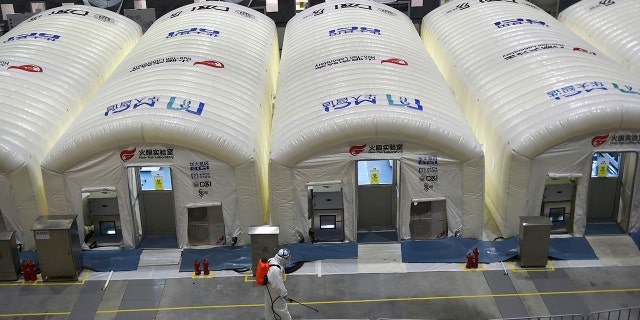 A worker disinfects the flooring outside the inflated cabins at the pop-up Huo-Yan Laboratory set up in an expo center to test samples for covid-19 virus in Nanjing in east China's Jiangsu province Wednesday, July 28, 2021.