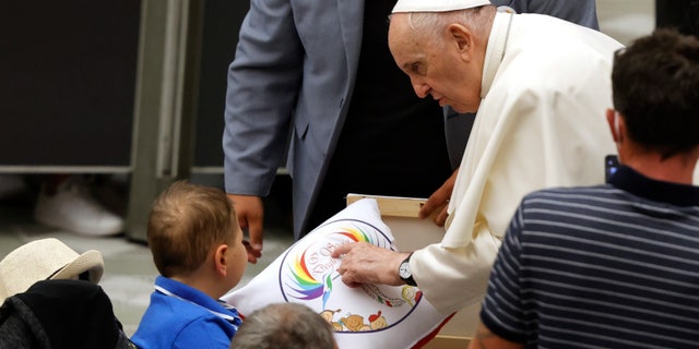 Pope Francis greets a child at the end of his weekly general audience in the Paul VI hall at the Vatican, Wednesday, Aug. 4, 2021. Pope Francis on Wednesday resumed his routine of weekly audiences with the general public a month after he underwent bowel surgery, expressing his desire to visit someday Lebanon, as he recalled the first anniversary of the devastating Beirut port explosion. (AP Photo/Riccardo De Luca)