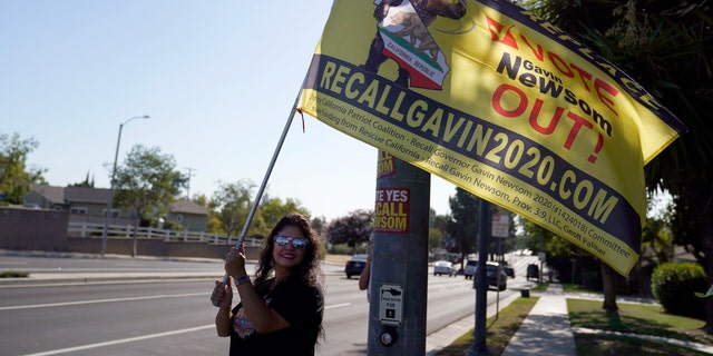 A supporter of the California recall of Gov. Gavin Newsom holds a sign outside of a debate by Republican gubernatorial candidates at the Richard Nixon Presidential Library Wednesday, Aug. 4, 2021, in Yorba Linda, Calif. Newsom faces a Sept. 14 recall election that could remove him from office. (AP Photo/Marcio Jose Sanchez)