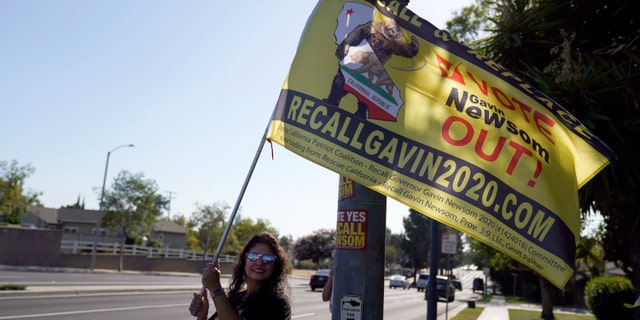 A supporter of the California recall of Gov. Gavin Newsom holds a sign outside of a debate by Republican gubernatorial candidates at the Richard Nixon Presidential Library Wednesday, Aug. 4, 2021, in Yorba Linda, Calif. Newsom faces a Sept. 14 recall election that could remove him from office. (AP Photo/Marcio Jose Sanchez)