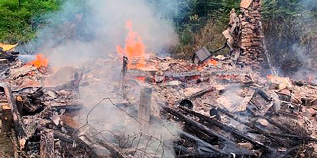 In this photo provided by the Canterbury (New Hampshire) Fire Department, smoke rises Wednesday, Aug. 4, 2021, from the burnt remains of a cabin in Canterbury, N.H., inhabited by 81-year-old David Lidstone, who for 27 years has lived in the woods of New Hampshire along the Merrimack River in the once small, solar-paneled cabin.