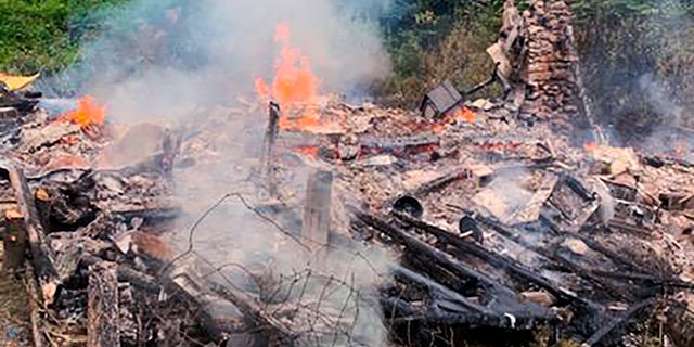 In this photo provided by the Canterbury (New Hampshire) Fire Department, smoke rises Wednesday, Aug. 4, 2021, from the burnt remains of a cabin in Canterbury, N.H., inhabited by 81-year-old David Lidstone, who for 27 years has lived in the woods of New Hampshire along the Merrimack River in the once small, solar-paneled cabin.