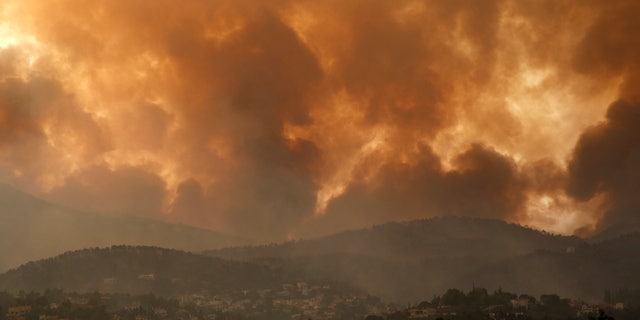 Smoke spreads over Parnitha mountain during a wildfire in Ippokratios Politia village, about 35 kilometres (21 miles), northern Athens, Greece, Friday, Aug. 6, 2021. Thousands of people fled wildfires burning out of control in Greece and Turkey on Friday, including a major blaze just north of the Greek capital of Athens that claimed one life, as a protracted heat wave left forests tinder-dry and flames threatened populated areas and electricity installations. (AP Photo/Lefteris Pitarakis)