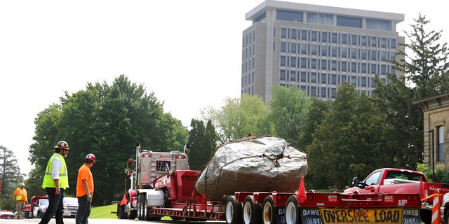 A flatbed trailer pull away from Observatory Hill with Chamberlin Rock in tow in Madison, Wis., Friday, Aug. 6, 2021. The University of Wisconsin is removing the 70-ton boulder from its Madison campus at the request of minority students who view the rock as a symbol of racism. Chamberlin Rock, on the top of Observatory Hill, is named after Thomas Crowder Chamberlin, a geologist and former university president. (Kayla Wolf/Wisconsin State Journal via AP)