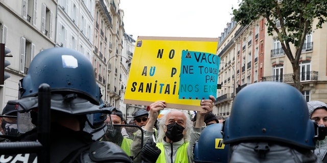 Anti-vax protesters face police during a protest against the vaccine and vaccine passports, in Paris, France, Saturday Aug. 7, 2021.