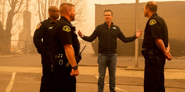 California Gov. Gavin Newsom speaks with law enforcement personnel while surveying damage to Greenville, which suffered extensive structure loss during the Dixie Fire, on Saturday, Aug. 7, 2021, in Plumas County, California. (Associated Press)