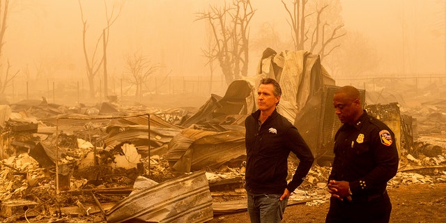 California Gov. Gavin Newsom surveys Greenville homes leveled by the Dixie Fire on Saturday, Aug. 7, 2021, in Plumas County, California. Accompanying him is Cal Fire Assistant Region Chief Curtis Brown. (Associated Press)