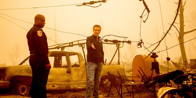 California Gov. Gavin Newsom examines a scorched utility pole while surveying Dixie Fire damage in Greenville on Saturday, Aug. 7, 2021, in Plumas County, California. Accompanying him is Cal Fire Assistant Region Chief Curtis Brown. (Associated Press)