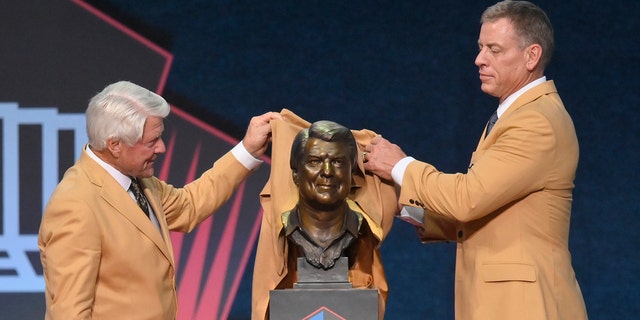 Jimmy Johnson, left, a member of the Pro Football Hall of Fame Centennial Class, shows off his bust with presenter Troy Aikman during the Pro Football Hall of Fame induction ceremony on Saturday August 7, 2021 in Canton, Ohio.  (Associated press)